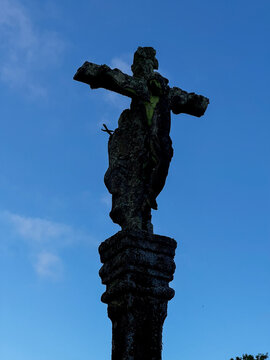 Weathered traditional stone cruceiro cross silhouetted against a blue sky on the Camino de Santiago in Spain