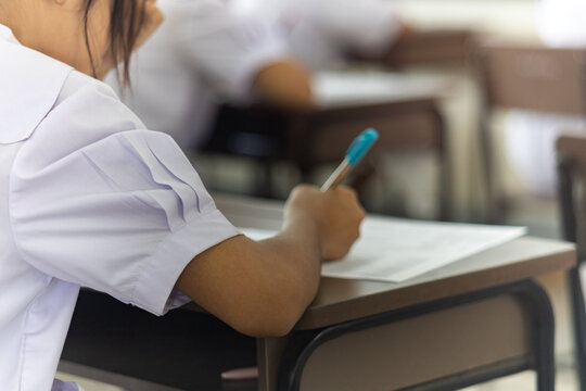 Students reading exam answer sheets exercises in classroom of school with headache and stress