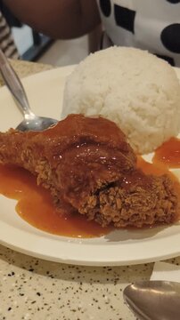 Fried chicken leg with sauce and white rice on plate