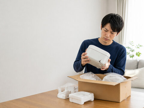 Man Looking at an Item with a Concerned Expression after Unpacking