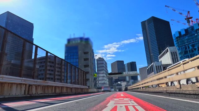 首都高速道路の都心環状線から望む高層ビル群と眩しい太陽の風景