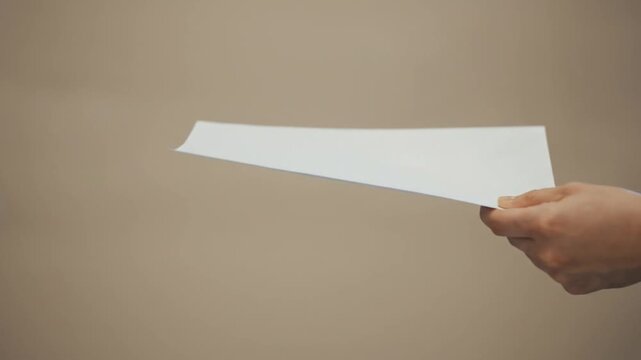 A close-up video shows a hand passing a white sheet of paper to another person in a suit, capturing a formal document exchange against a neutral background.