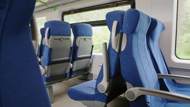 Comfortable blue reclining train seats inside modern passenger carriage with natural daylight