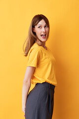 Obraz premium Smiling woman with brown hair wearing a yellow shirt, standing against a yellow background. Bright, cheerful mood, fashion portrait, casual style, studio lighting.