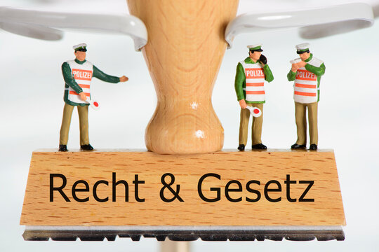 Ein Holzstempel ist beschriftet mit dem Aufdruck:  Recht und Gesetz und einigen Polizei-Modellfiguren