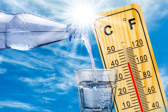 Ein Thermometer zeigt sehr hohe Temperatur in der Sommerhitze und eine Wasserflasche mit Glas