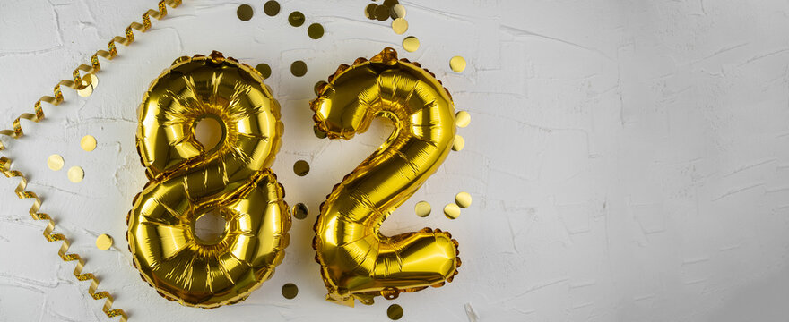 Yellow Gold foil balloon number eighty-two on white background. Birthday card with lettering 82. Anniversary concept. For anniversary, birthday, wedding event, new year celebration. Banner