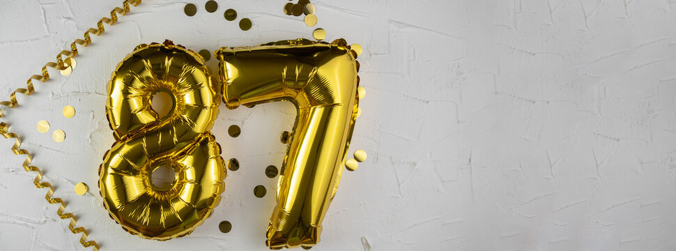 Yellow Gold foil balloon number eighty-seven on white background. Birthday card with lettering 87. Anniversary concept. For anniversary, birthday, wedding event, new year celebration.