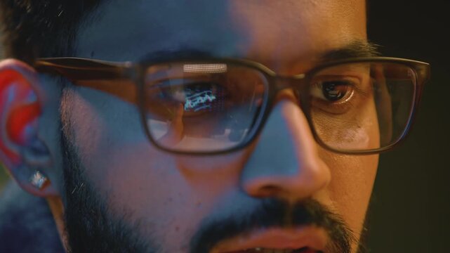 Male eyes in glasses looking at financial graph light reflection Arabian Indian business man guy businessman analyzing stats trading cryptocurrency reflected screen in eyeglasses cybercrime at night