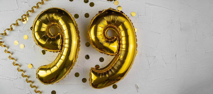 Yellow Gold foil balloon number ninety-nine on white background. Birthday card with lettering 99. Anniversary concept. For anniversary, birthday, wedding event, new year celebration. Banner