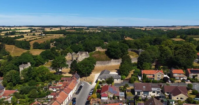 Aerial footage of Pickering Castle in Pickering North Yorkshire England showcasing the well preserved medieval Norman fortress with defensive walls central keep surrounding woodland and countryside