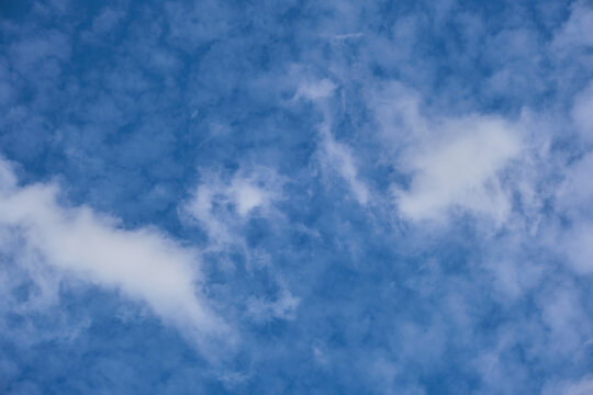 Beautiful bright blue sky filled with soft light white cirrus clouds on clear sunny day.