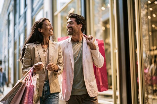 Couple walking together with shopping bags outside retail store in the city