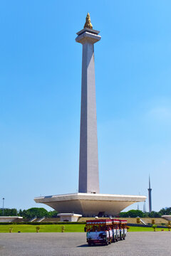 Monas National Monument in Jakarta, Indonesia, with a tourist bus in the foreground