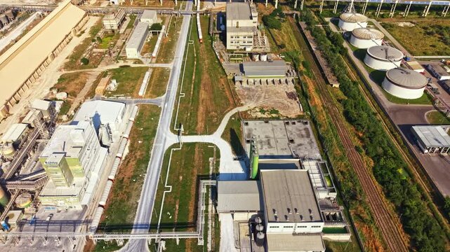 Large industrial area shows multiple buildings, pathways, and equipment. Clear skies and daylight emphasize the organized layout of the site. Activity and operations are evident in the vicinity.