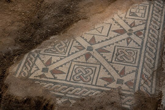 Close-up of ancient mosaic floor with geometric patterns, archaeological texture.