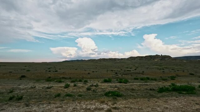 Off-road vehicle view of expansive landscape with clouds and distant hills