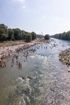 People cooling off in a river in the middle of a city on a hot day. Munich, Germany