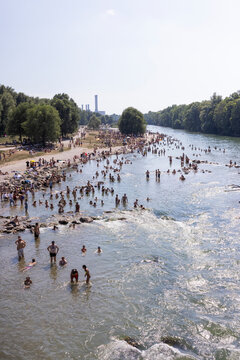 People cooling off in a river in the middle of a city on a hot day. Munich, Germany