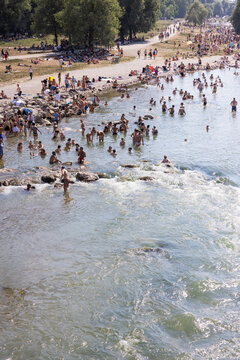 People cooling off in a river in the middle of a city on a hot day. Munich, Germany