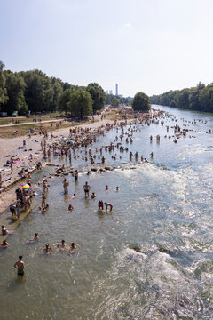 People cooling off in a river in the middle of a city on a hot day. Munich, Germany