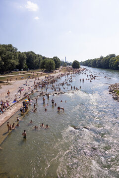 People cooling off in a river in the middle of a city on a hot day. Munich, Germany