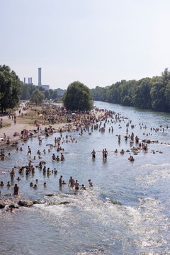 People cooling off in a river in the middle of a city on a hot day. Munich, Germany