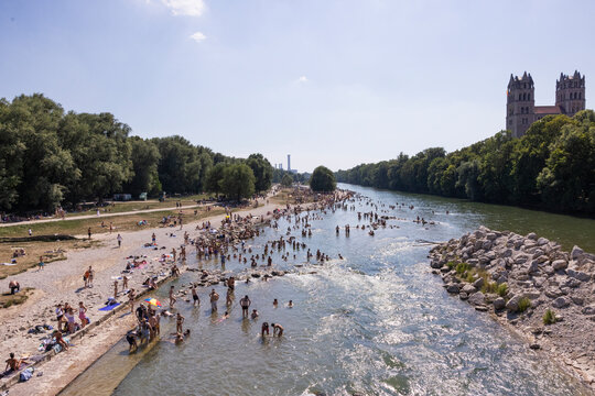 People cooling off in a river in the middle of a city on a hot day. Munich, Germany