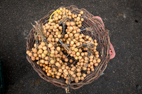 Cestos com pitombas frescas &agrave; venda em feira livre brasileira, destacando uma fruta nativa muito apreciada no Nordeste e o com&eacute;rcio tradicional em mercado popular.