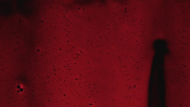 Macro close up of red liquid with dark bubbles and fluid motion, abstract science experiment background texture