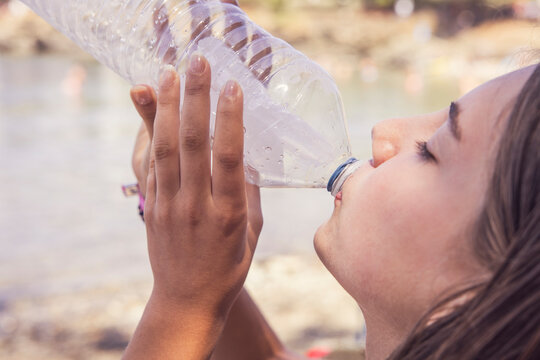 Young Girl Drinking Water from a Plastic Bottle on a Hot Summer Day.