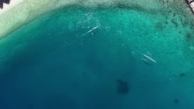 Top Down Aerial View of Two Rowers Rowing Boats in Clear Turquoise Sea Water