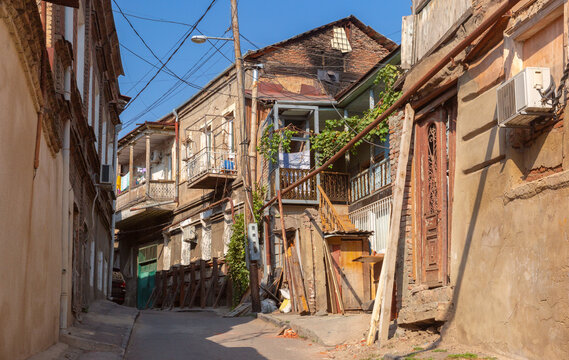 Narrow street lined with traditional residential houses, wooden balconies and aged architecture in the historic district of Tbilisi, Georgia.
