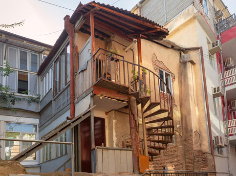 Narrow street lined with traditional residential houses, wooden balconies and aged architecture in the historic district of Tbilisi, Georgia.