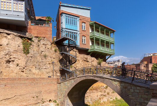 Stone pedestrian bridge with traditional wooden balconies and hillside houses in the historic district of Tbilisi, Georgia.