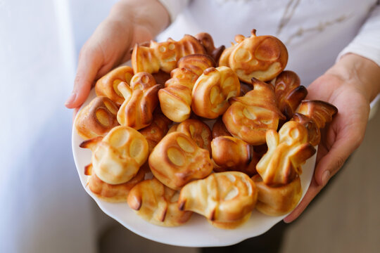 Group members share a plate filled with cookies formed like various animals and figures. The setting is a home kitchen and it is afternoon