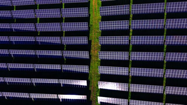 Overhead shadow pattern of solar panel rows, Bulgaria. Top down view of long dark panel lines separated by narrow grass paths.