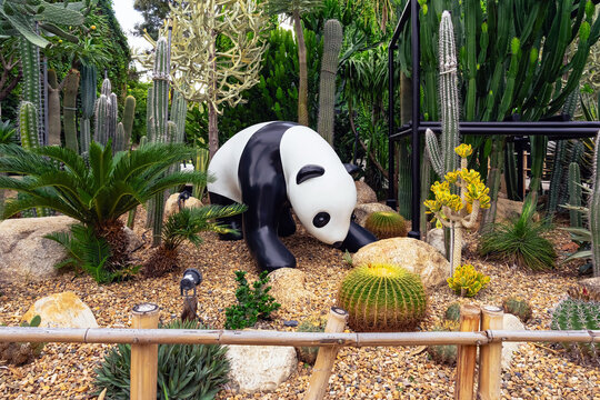KANCHANABURI, THAILAND - JUNE 12, 2026: Artificial giant giant panda statue installation posing on gravel and stone ground, surrounded by various desert plants, and succulents at CHAN nature cafe.