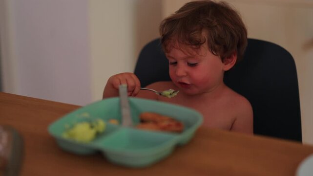 Toddler eating hot meal during family mealtime, highlighting self feeding, sensory learning and everyday childhood