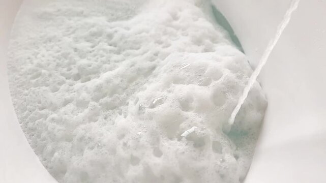  Water Pouring into a White Bathtub Creating Soap Foam and Bubbles