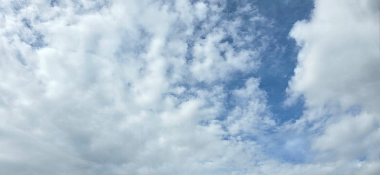 The sky is filled with scattered white clouds. These are cumulus or stratocumulus clouds, indicating clear weather, but with possible increased humidity in the atmosphere.
