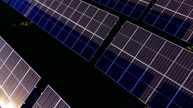 Solar panel grid seen from directly above. Close overhead shot of dark blue modules with faint blue light reflections.