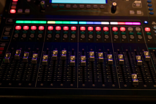Close-up of an audio mixing console volume control panel.
