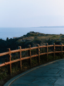 Coastal Cliff Walkway with Wooden Fence and Ocean View at Sunset