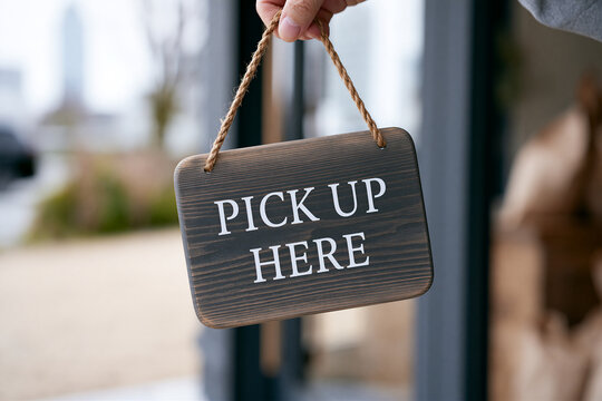 Wooden PICK UP HERE sign held outside a storefront