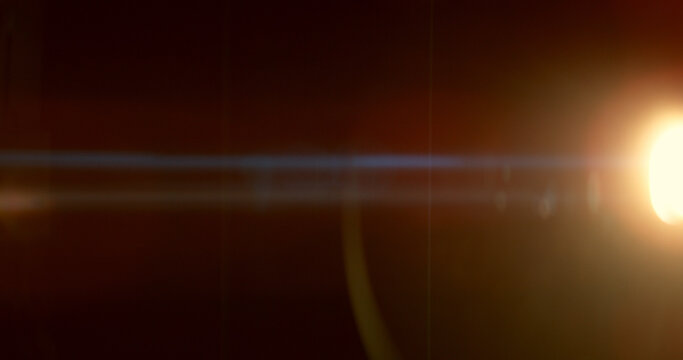 Warm anamorphic lens flare overlay featuring a golden light source, blue horizontal light streak, realistic optical reflections and subtle glow on a black background. Premium VFX asset.