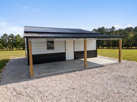 White Metal Building with Wooden Covered Lean-To on Gravel Pad in Rural Field