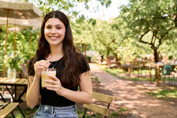 Fototapeta premium Summer vibes fill the air as a young woman enjoys a refreshing drink in lush greenery