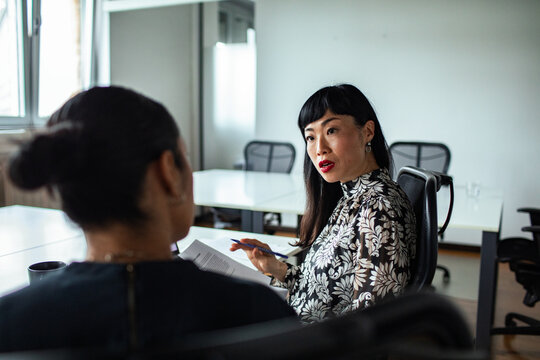 Two businesswomen discussing documents in modern office