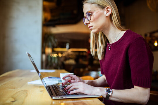 Focused woman working on laptop in cafe